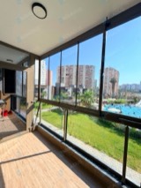 Havuz ve bahçe manzaralı balkonda koyu profilli cam balkon