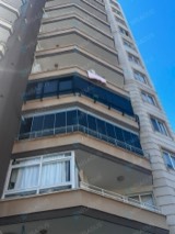 Yüksek binada iki balkonda koyu profilli cam balkon