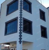 Beyaz cepheli binada koyu çerçeveli cam kapatmalar