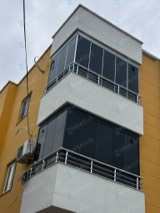 Sarı cepheli binada köşe balkonlarda koyu camlı cam balkon