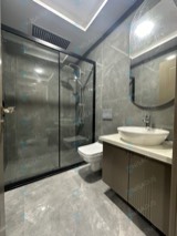 Siyah profilli düz sürgülü duşakabin, şeffaf cam, gri mermer desenli banyo