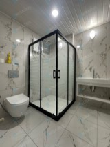Siyah profilli şerit camlı köşe duşakabin, asma klozetli banyo